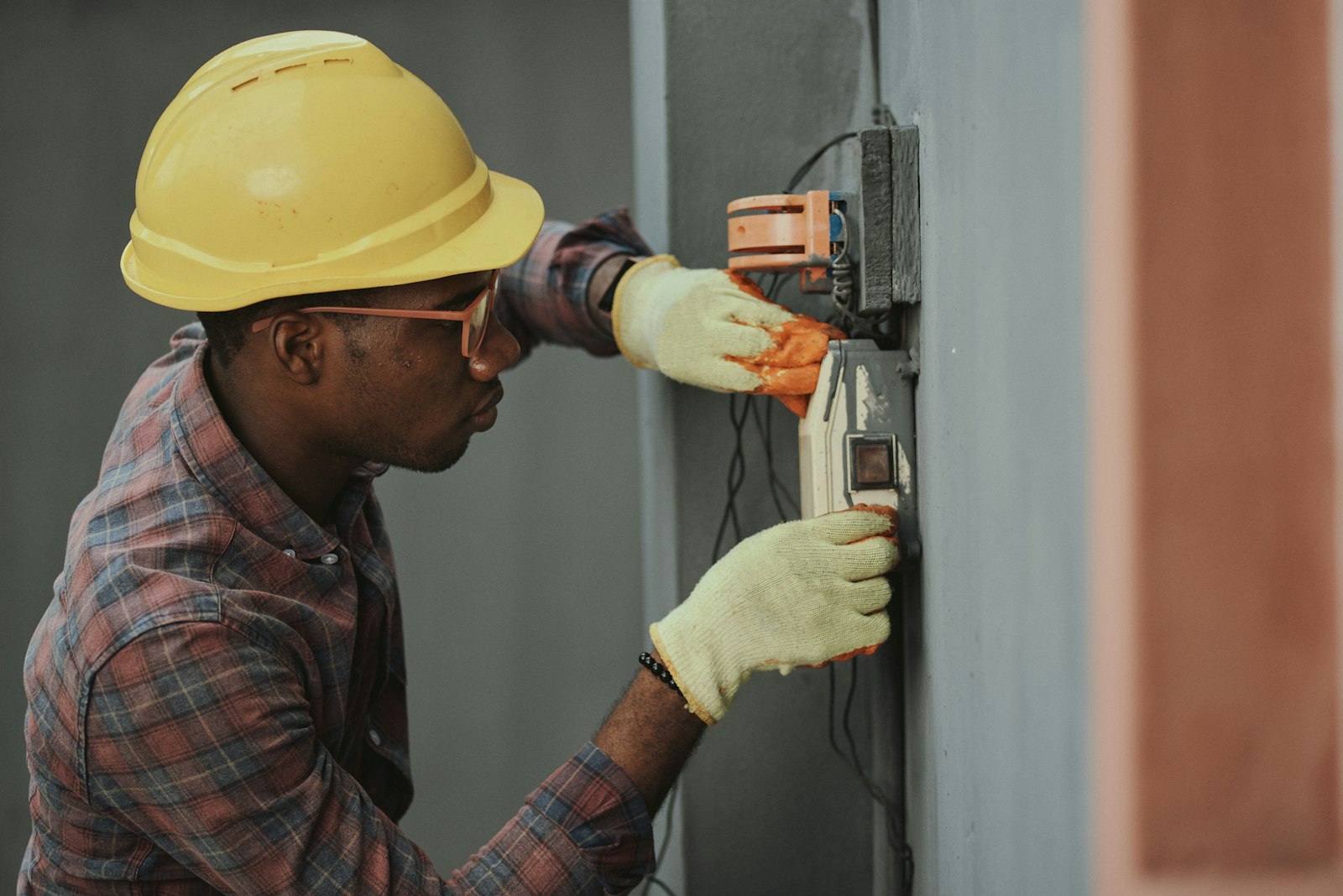 Technician wearing a hard hat servicing electrical panel for HVAC and home services