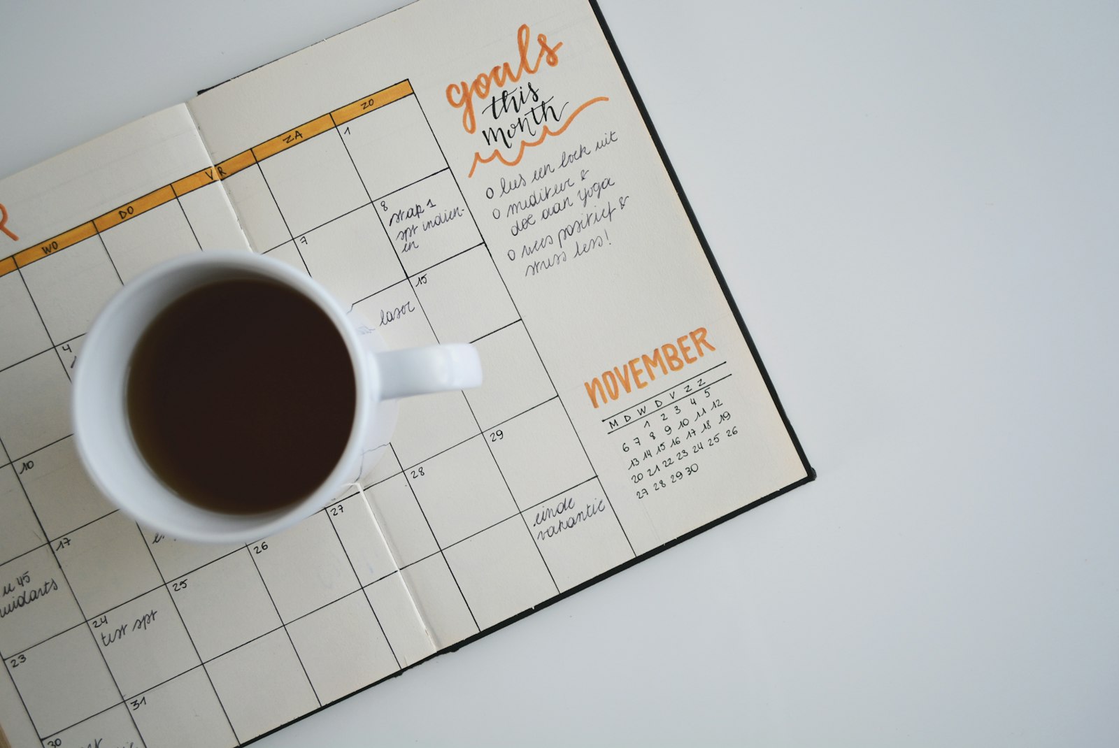 Open monthly planner with appointments and a coffee cup on a clean desk